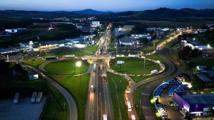 Vista aérea de rodovia e entroncamento ao anoitecer, com tráfego de veículos